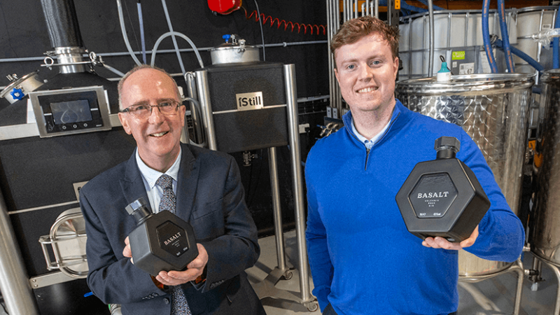 Two men standing in a distillery, they are both holding gin products